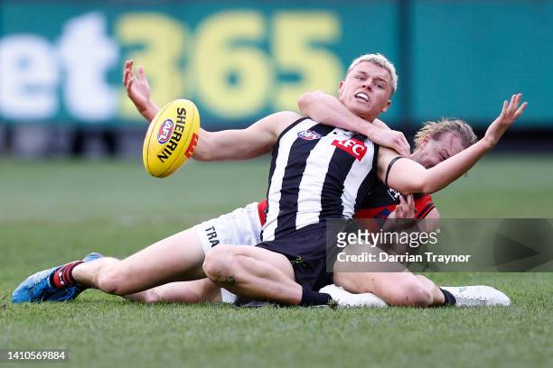 Mason Redman of the Bombers tackles Jack Ginnivan of the Magpies during the round 19 AFL match between the Collingwood Magpies and the Essendon...