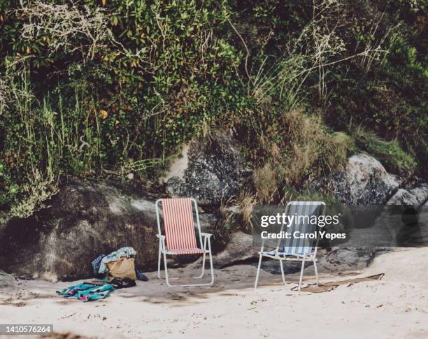 a traditional style striped deckchair sits on a sandy beach. - ice bucket stockfoto's en -beelden