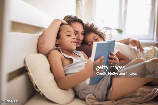une mère et ses enfants lisent un livre - stéréotype de la classe moyenne photos et images de collection