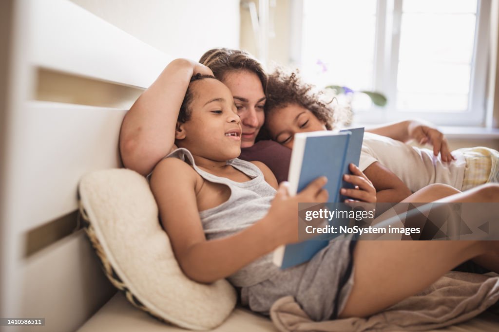 Madre e i suoi bambini che leggono un libro