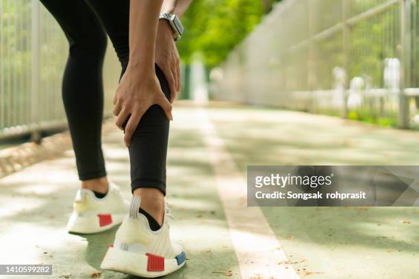 shot of a woman massaging an injury in her leg - sports pain bildbanksfoton och bilder
