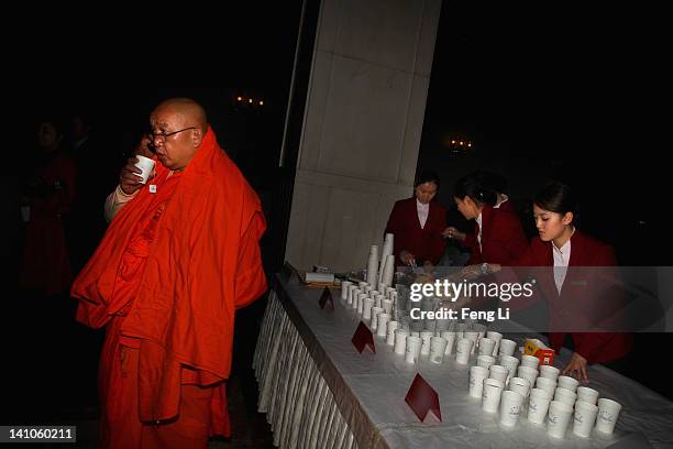 Delegate of Buddhist monk drinks during the third plenary meeting of the 11th National Committee of the Chinese People's Political Consultative...