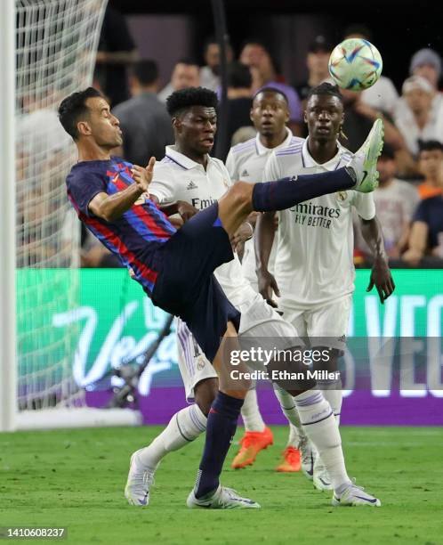 Sergio Busquets of Barcelona kicks the ball under pressure from Aurélien Tchouaméni and Eduardo Camavinga of Real Madrid during their preseason...