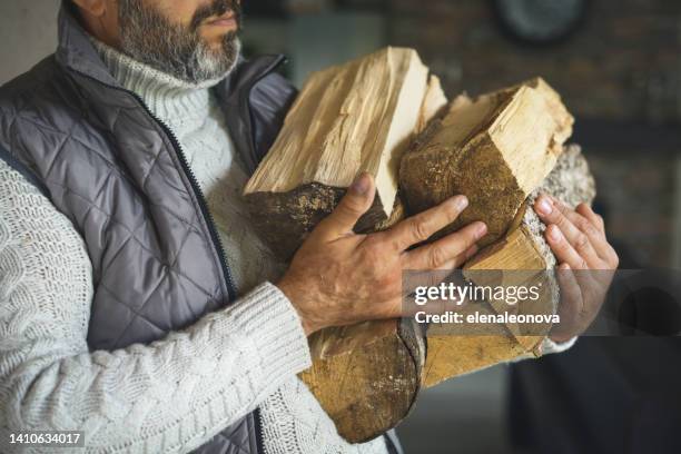 mature adult man carrying firewood - houtstapel stockfoto's en -beelden