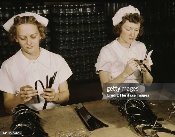Two Navy wives, Eva Herzberg and Elve Burnham, entered war work after their husbands joined the service, Glenview, Ill. They assemble bands for blood...