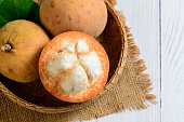 Top view of Fresh Santol fruits on bamboo basket and on white wood background,