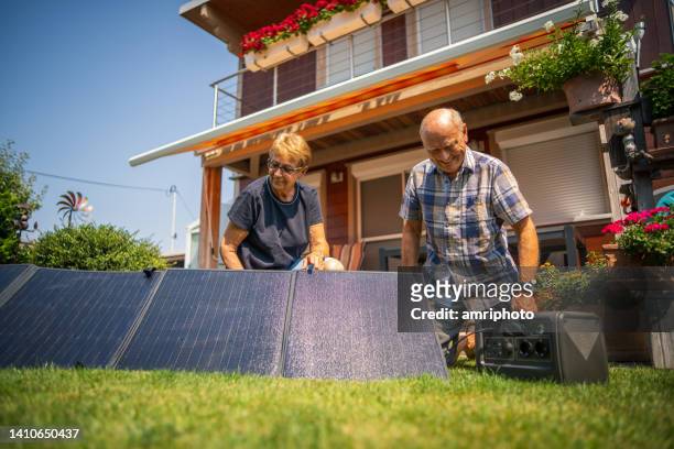 senior couple pleased with new portable solar plant - autarkie stockfoto's en -beelden
