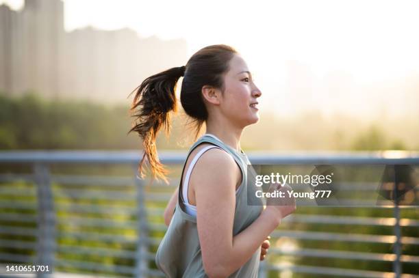 asian young woman running in the city street in the morning - china athlete woman stock pictures, royalty-free photos & images