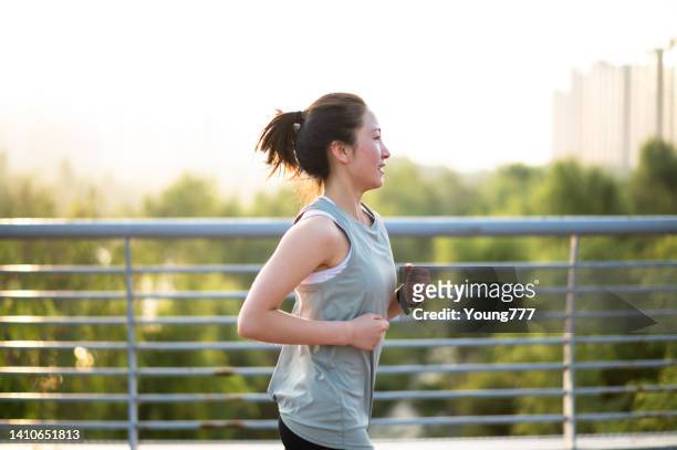朝、街の通りを走るアジアの若い女性 - woman jogging ストックフォトと画像