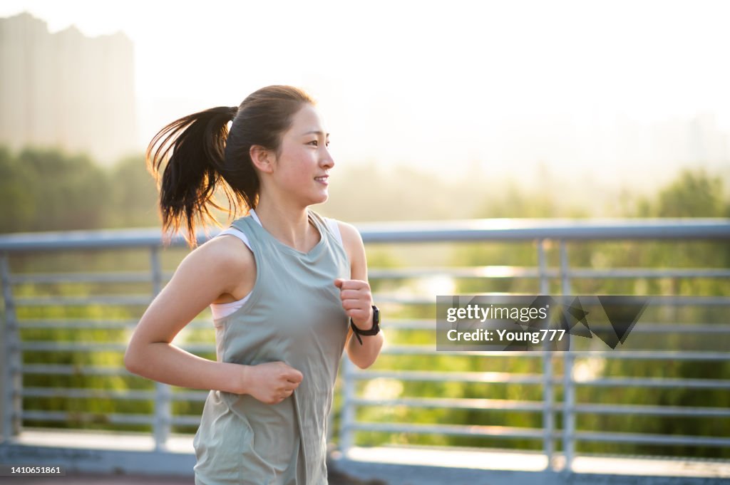 Asian young woman running in the city street in the morning