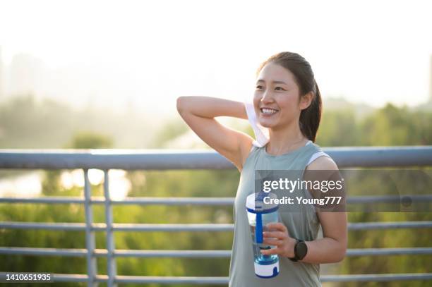 asian young woman is wiping sweat after running in city street in morning - china athlete woman stock pictures, royalty-free photos & images