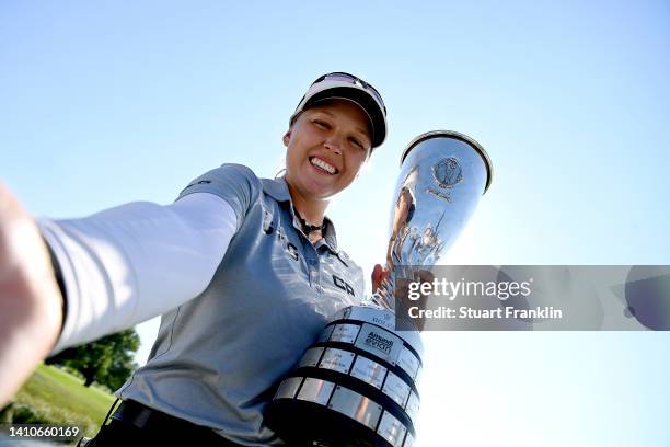 Brooke M. Henderson of Canada imitates a selfie as she poses for a photo with her trophy after winning the The Amundi Evian Championship during day...