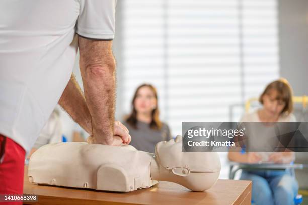 instructor demonstrating chest compressions on a cpr dummy. - first aid training stock pictures, royalty-free photos & images