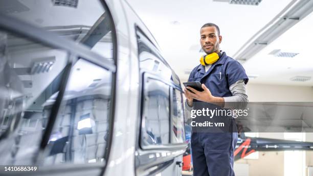 african american mechanic standing near jet and looking at camera, side view - vliegtuigmonteur stockfoto's en -beelden