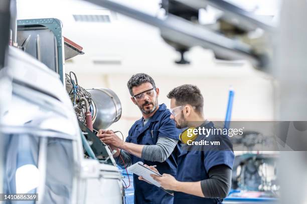 junge luftfahrtmechaniker, die triebwerk mit mittlerem schuss reparieren - mechanics stock-fotos und bilder