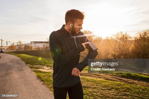 young man runner athlete with arm band using smart phone - armband stock pictures, royalty-free photos & images