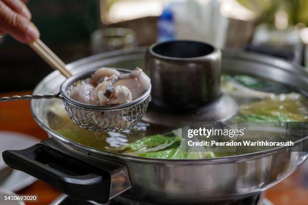 dipping slice of fish in metal strainer into boiled soup inside hot pot - lancashire hotpot stock pictures, royalty-free photos & images