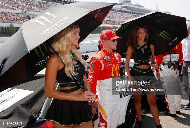 Ty Gibbs, driver of the McDonald's Toyota, poses with Monster Energy models on the grid prior to the NASCAR Cup Series M&M's Fan Appreciation 400 at...