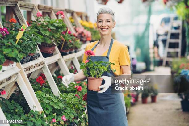 jardinier joyeux travaillant dans une jardinerie - magasin de fleurs photos et images de collection