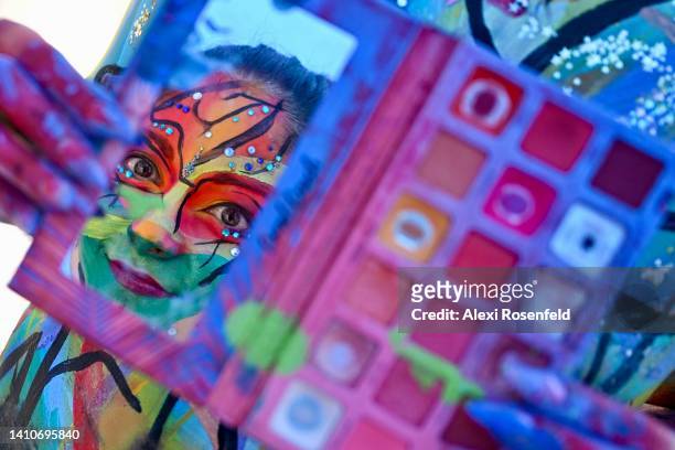 Artist Dorothy Rojas looks in a makeup mirror to add details to her painted face during the 9th annual ‘NYC Body Painting Day’ in Union Square on...