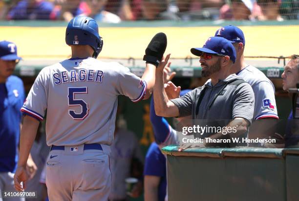 Corey Seager of the Texas Rangers is congratulated by manager Chris Woodward after Seager scored against the Oakland Athletics in the top of the...