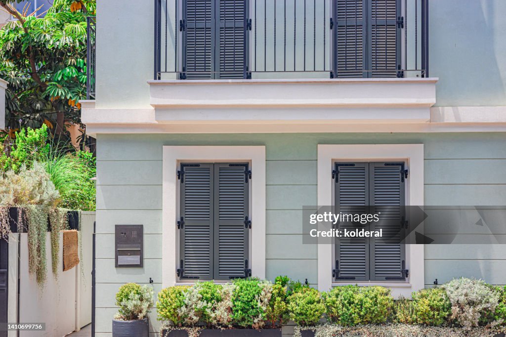 Renovated luxury apartment building with traditional jalousies windows, decorated with potted flowers