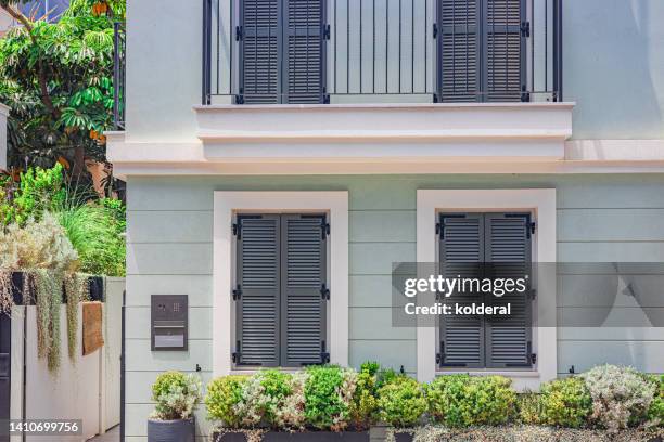 renovated luxury apartment building with traditional jalousies windows, decorated with potted flowers - jalousie fotografías e imágenes de stock