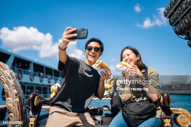 tourist couple taking selfie with smart phone while experiencing and eating street food during their travel - asian tourist bildbanksfoton och bilder