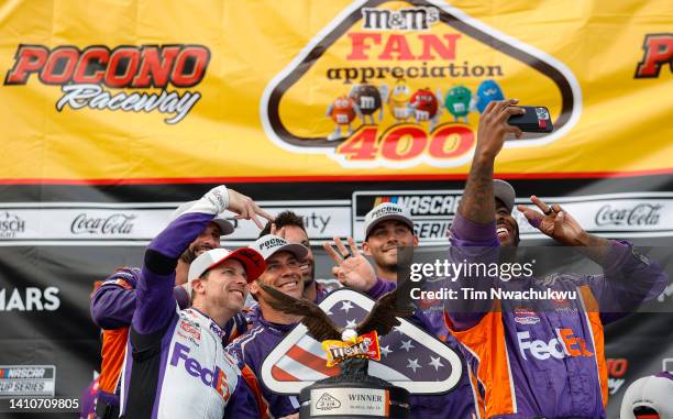 Denny Hamlin, driver of the FedEx Office Toyota, and crew take a selfie in victory lane after winning the NASCAR Cup Series M&M's Fan Appreciation...