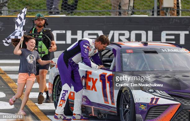 Taylor Hamlin celebrates with the checkered flag after her father, Denny Hamlin, driver of the FedEx Office Toyota, won the NASCAR Cup Series M&M's...