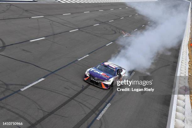 Denny Hamlin, driver of the FedEx Office Toyota, celebrates with a burnout after winning the NASCAR Cup Series M&M's Fan Appreciation 400 at Pocono...
