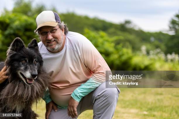 man is thrilled to have an animal encounter with a wolf at wildlife sanctuary - black wolf stock pictures, royalty-free photos & images