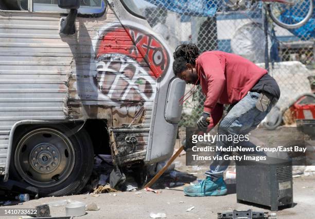 Alan Walker clears debris from underneath a recreational vehicle at the Wood Street homeless encampment so it can be towed in Oakland, Calif., on...