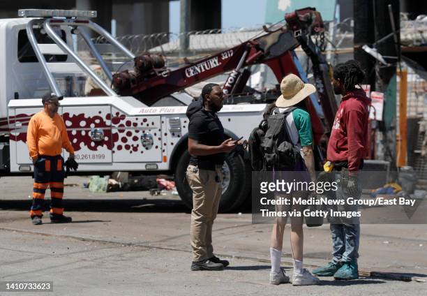 Alan Walker right, talks with people as a recreational vehicle is towed at the Wood Street homeless encampment in Oakland, Calif., on Thursday, July...