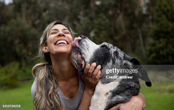 donna felice che gioca con il suo cane all'aperto - leccare foto e immagini stock