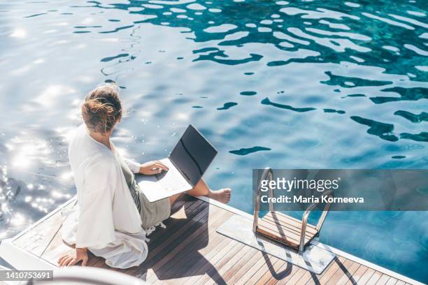 woman on a luxury yacht working during vacation. - yachting lifestyle stock pictures, royalty-free photos & images