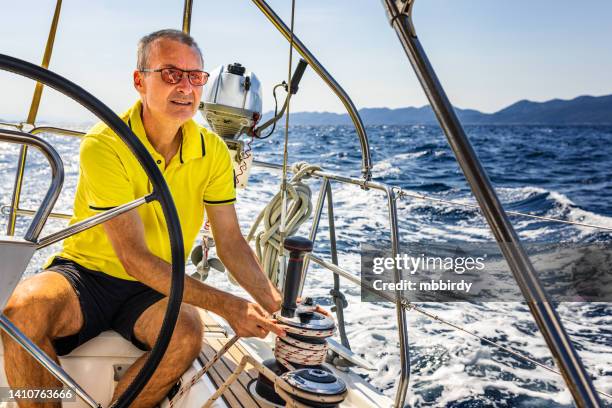 sailing crew member trimming genoa sail on sailboat - capitão-de-equipa imagens e fotografias de stock