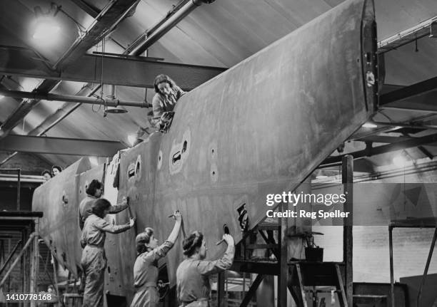 Female workers apply doped Madapollam fabric to the wing section of a de Havilland DH98 Mosquito twin-engined multirole fighter-bomber aircraft...