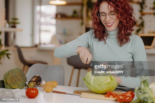 mujer joven preparando comida en casa - cabbage family fotografías e imágenes de stock