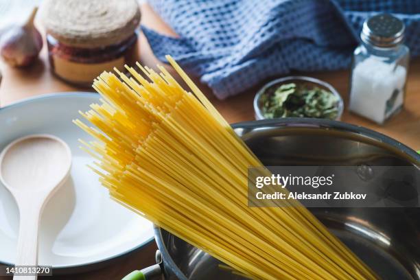 raw spaghetti or pasta in a saucepan for cooking and boiling food, at home or in a cafe. vegetarian and vegan food. home life. ethical consumption. italian cuisine. - dry pasta stock pictures, royalty-free photos & images