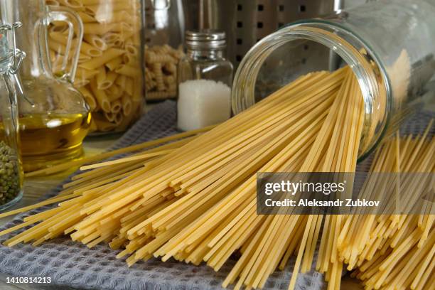 cooking italian pasta at home. raw penne rigate pasta in a glass jar for storage and on the kitchen table. vegetarian and vegan food. cooking lessons. sustainable development, ethical consumption. step-by-step instructions, do it yourself. step 1. - spaghetti stock pictures, royalty-free photos & images