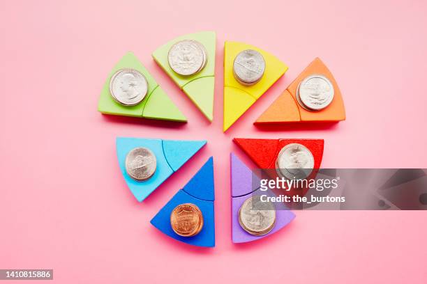 pie chart made of colorful building blocks and stacks of american dollar coins on pink background - building block infographic stock pictures, royalty-free photos & images
