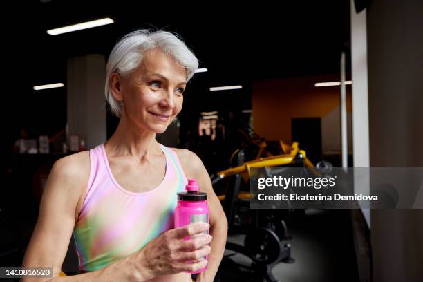 aged female athlete drinking water during break - pause button stock pictures, royalty-free photos & images