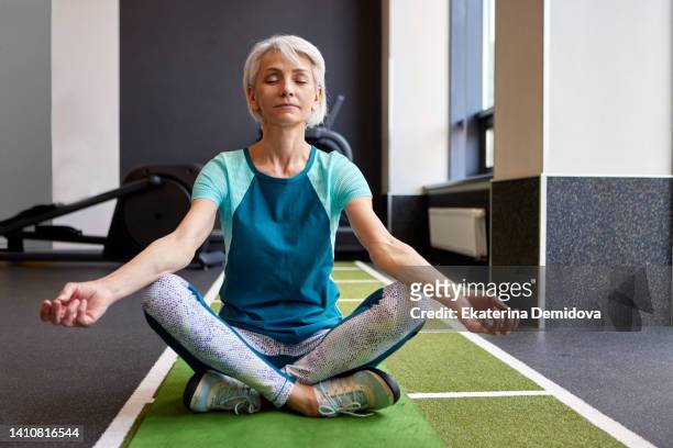 senior female meditating in gym - relief carving stock pictures, royalty-free photos & images