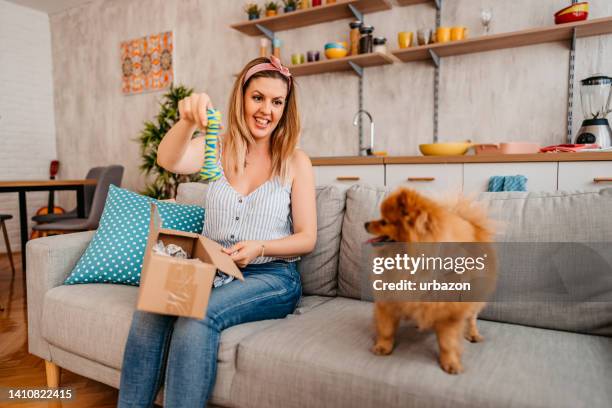 young woman unpacking a package for her dog - dog's toy stockfoto's en -beelden