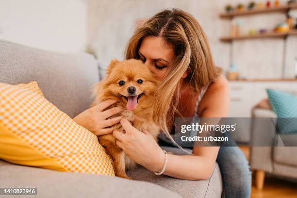 young woman cuddling with her dog - pomeranian puppy stock pictures, royalty-free photos & images