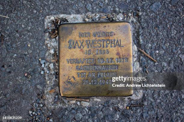 Small bronze plaque embedded in a residential neighborhood sidewalk, known as a stumbling stone, reminds German citizens of the atrocities of the...
