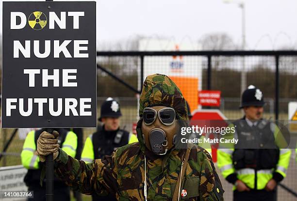 Masked protester holds a placard at the gates to the Hinkley Point nuclear power station, as demonstrators gather to mark the first anniversary of...