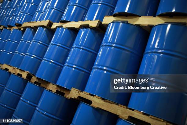 blue metal oil barrels stacked in a warehouse - oil stockfoto's en -beelden