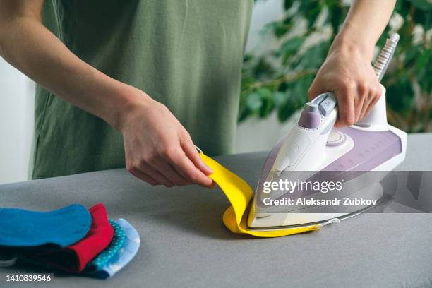 a woman or a girl irons a reusable protective mask. prevention and protection from infection with influenza viruses and infection, covid-19, smallpox monkeys. disinfection, disinfection and sterilization of masks for reuse. precautions. - smallpox epidemic stock pictures, royalty-free photos & images